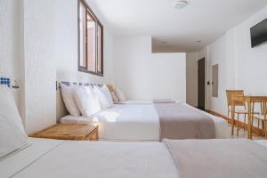 a white bedroom with two beds and a window at Pousada Porto Fino in Cabo Frio