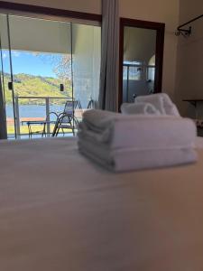 una pila de toallas blancas sentadas encima de una cama en Pousada Recanto Rainha do Lago, en Capitólio