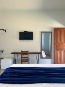a bedroom with a bed and a table and a mirror at Pousada Recanto Rainha do Lago in Capitólio