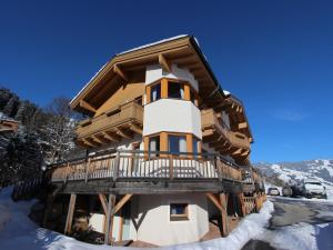 a log home with a deck in the snow at Traumlage Ski in - Ski out in Saalbach Hinterglemm