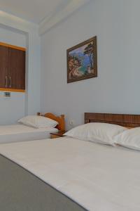 two beds in a room with a picture on the wall at Vila EN AD in Ksamil