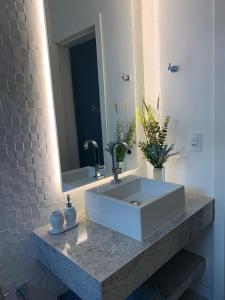 een badkamer met een witte wastafel en een spiegel bij Suíte completa próximo a Capitólio e Canastra in Piuí