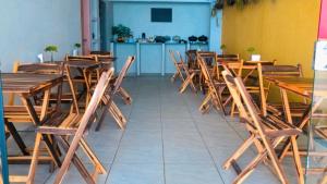 una fila de mesas y sillas de madera en un restaurante en Pousada Maré Alta Maceió en Maceió