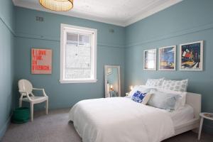 1 dormitorio azul con 1 cama y 1 silla en Modern Muse, Bellevue Hill, en Sídney
