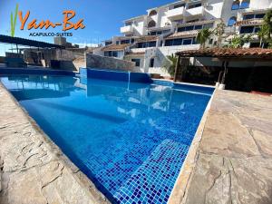 a swimming pool with blue water in front of a building at Suites Acapulco Yamba in Acapulco