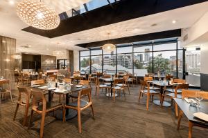 a restaurant with tables and chairs and large windows at Hotel Grand Chancellor Brisbane in Brisbane