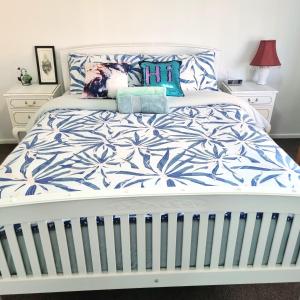 uma cama branca com lençóis e almofadas azuis e brancos em Spacious Room Near Christchurch Airport em Christchurch