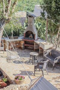 une terrasse avec une cheminée, des chaises et une balançoire dans l'établissement Villetta Munti Leuca, à Leuca