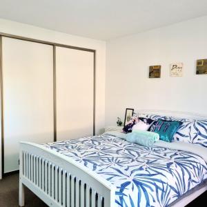 een witte slaapkamer met een bed met blauwe en witte lakens bij Spacious Room Near Christchurch Airport in Christchurch