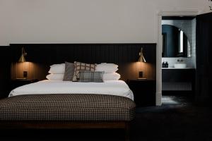um quarto com uma cama grande com lençóis brancos e almofadas em The Victoria Hotel Rutherglen em Rutherglen