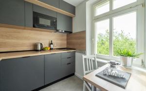 eine Küche mit grauen Schränken, einem Tisch und einem Fenster in der Unterkunft Apartment an der Uni Klinik in Magdeburg