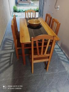 uma mesa de madeira com cadeiras e uma tigela sobre ela em Casa PHB na Parnaíba