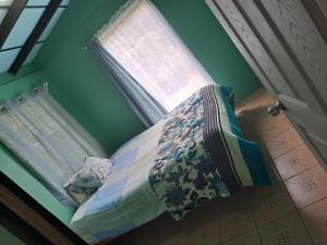 Cama pequeña en habitación verde con ventana en Casa #6 cabinas san gerardo, en San José