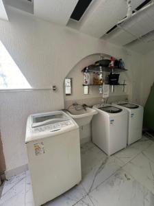 a laundry room with three washing machines and a window at Coliving Brooklin e Chácara Santo Antonio in Sao Paulo