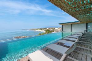 a swimming pool with lounge chairs and the ocean at Ancora Punta Mita in Punta Mita