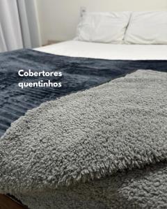 a bed with a grey rug on top of it at Casa em Condominio próximo trevo Cataratas em Cascavel in Cascavel