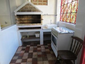 eine Küche mit Herd, Spüle und Stuhl in der Unterkunft Suites Delicia in Passa Quatro