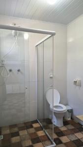 ein Badezimmer mit einem WC und einer Glasduschkabine in der Unterkunft Suites Delicia in Passa Quatro