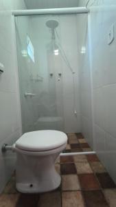 ein weißes Bad mit einer Dusche und einem WC in der Unterkunft Suites Delicia in Passa Quatro