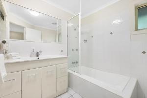 a white bathroom with a shower and a sink at Little Diggers in Coffs Harbour