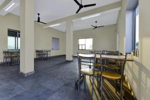 an empty room with chairs and tables and windows at OYO Hotel Ishwar in Jaipur
