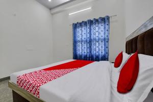 1 dormitorio con cama con almohadas rojas y cortinas azules en OYO Hotel Ishwar en Jaipur
