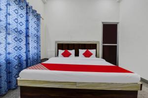 1 dormitorio con 1 cama con cortinas rojas y azules en OYO Hotel Ishwar en Jaipur