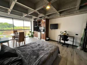 a bedroom with a bed and a table and a kitchen at Cercano al Aeropuerto y nuevo in Pereira