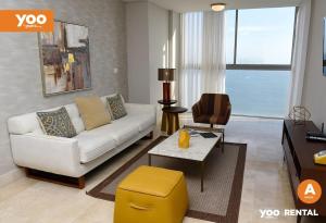 een woonkamer met een witte bank en een gele kruk bij Yoo Panama in Panama-Stad