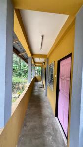 un pasillo de un edificio con una puerta rosa en Country house Pulai Holiday Village, en Gua Musang
