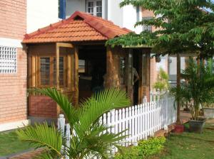 a wooden house with a white fence in a yard at Palmyrah Tenements in Mysore