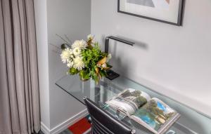 a glass table with a vase of flowers on it at Rydges Auckland in Auckland