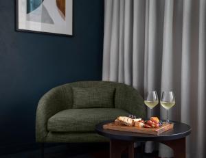 a table with a chair and two glasses of wine at Rydges Auckland in Auckland
