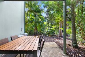 a wooden table and chairs on a patio with trees at Oceanique in Coffs Harbour