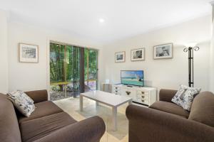 a living room with two couches and a tv at Oceanique in Coffs Harbour