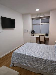 a bedroom with a bed and a desk and a television at Apartamento aconchegante in Brasília