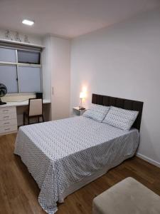 a bedroom with a large bed and a desk at Apartamento aconchegante in Brasília