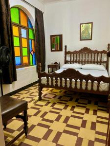 Casa Grande Hostal في ميديلين: غرفة نوم مع سرير ونافذة زجاجية ملطخة