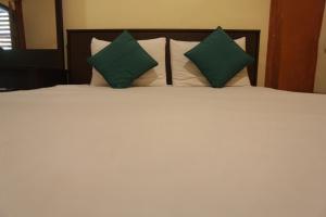 ein Bett mit grünen und weißen Kissen darauf in der Unterkunft Cinnamon Airport Residencies in Katunayaka