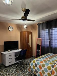 - une chambre avec un lit, un bureau et un ventilateur de plafond dans l'établissement Renda Residence, à Deabenekrom
