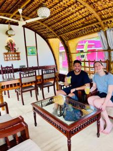 Ein Mann und eine Frau sitzen in einem Restaurant mit Getränken. in der Unterkunft Thara's Houseboat in Alappuzha