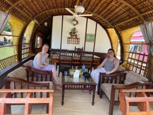 Dos mujeres sentadas en sillas en un restaurante en Thara's Houseboat en Alleppey