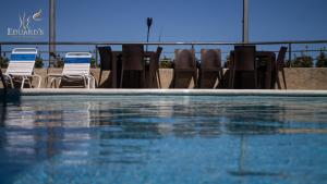 un grupo de sillas y una piscina con sillas y mesas en Hotel Eduards Suite, en Macuto