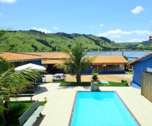 a swimming pool in front of a house at Pousada Recanto Rainha do Lago in Capitólio