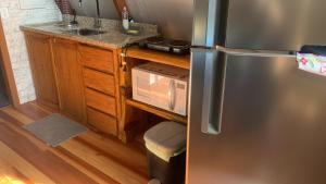 a kitchen with a stainless steel refrigerator and a sink at Chalés Roma in Santo Antônio do Pinhal