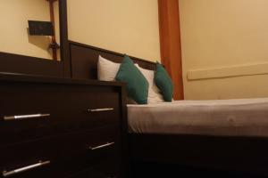 ein Schlafzimmer mit einem Bett mit grünen Kissen und einem Spiegel in der Unterkunft Cinnamon Airport Residencies in Katunayaka