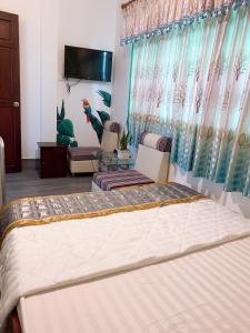 ein Schlafzimmer mit einem Bett und Stühlen sowie einem TV in der Unterkunft Nam Phương Hotel Sa Đéc in Sa Ðéc