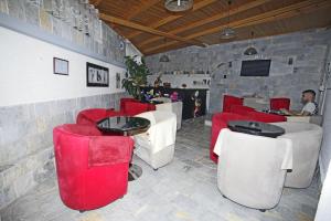 ein Restaurant mit roten Stühlen und ein Mann am Tisch in der Unterkunft Alen Bar Hotel in Tirana