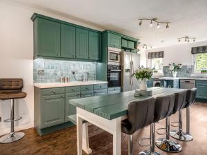 a kitchen with green cabinets and a table with chairs at Tigh Na Beannaich in Powmill