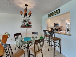 a dining room and kitchen with a glass table and chairs at Ocean Sands 1002 in St. Pete Beach